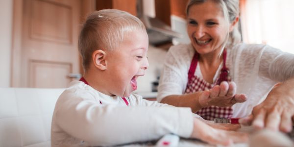 Ett skrattande barn bakar tillsammans med sin mamma i köket