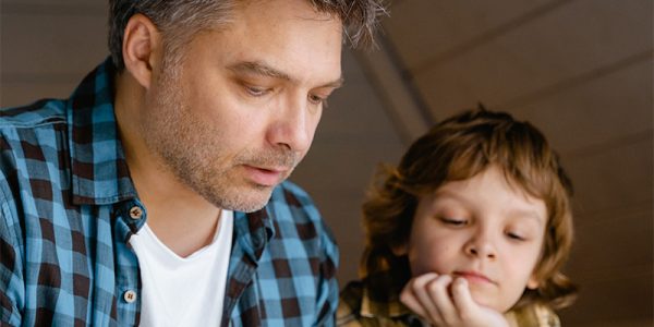 En pappa läser läxor tillsammans med sin son
